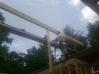 Carpenter setting a ridge beam over a new addition frame — Ice Dam Removal by Roofing Brothers in North East