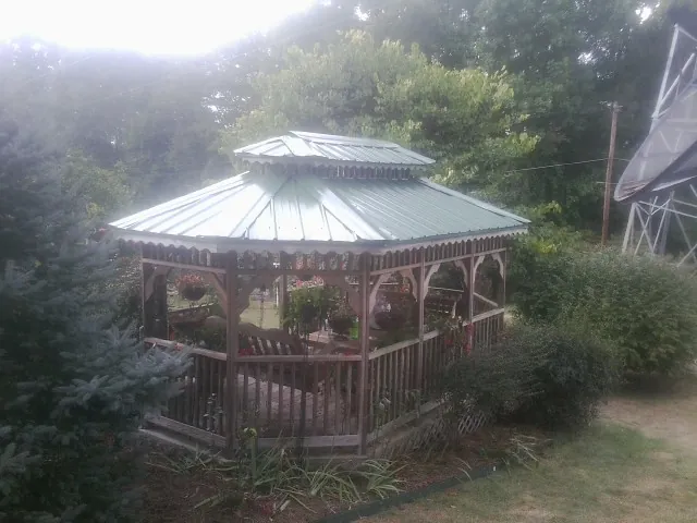 Green metal roof on a backyard gazebo surrounded by garden beds in North East