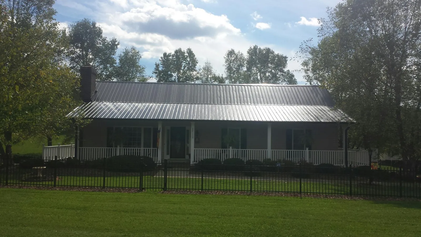 Gray metal roof on a brick ranch with a full width front porch — Gutter Guard Installation work by our crew in North East