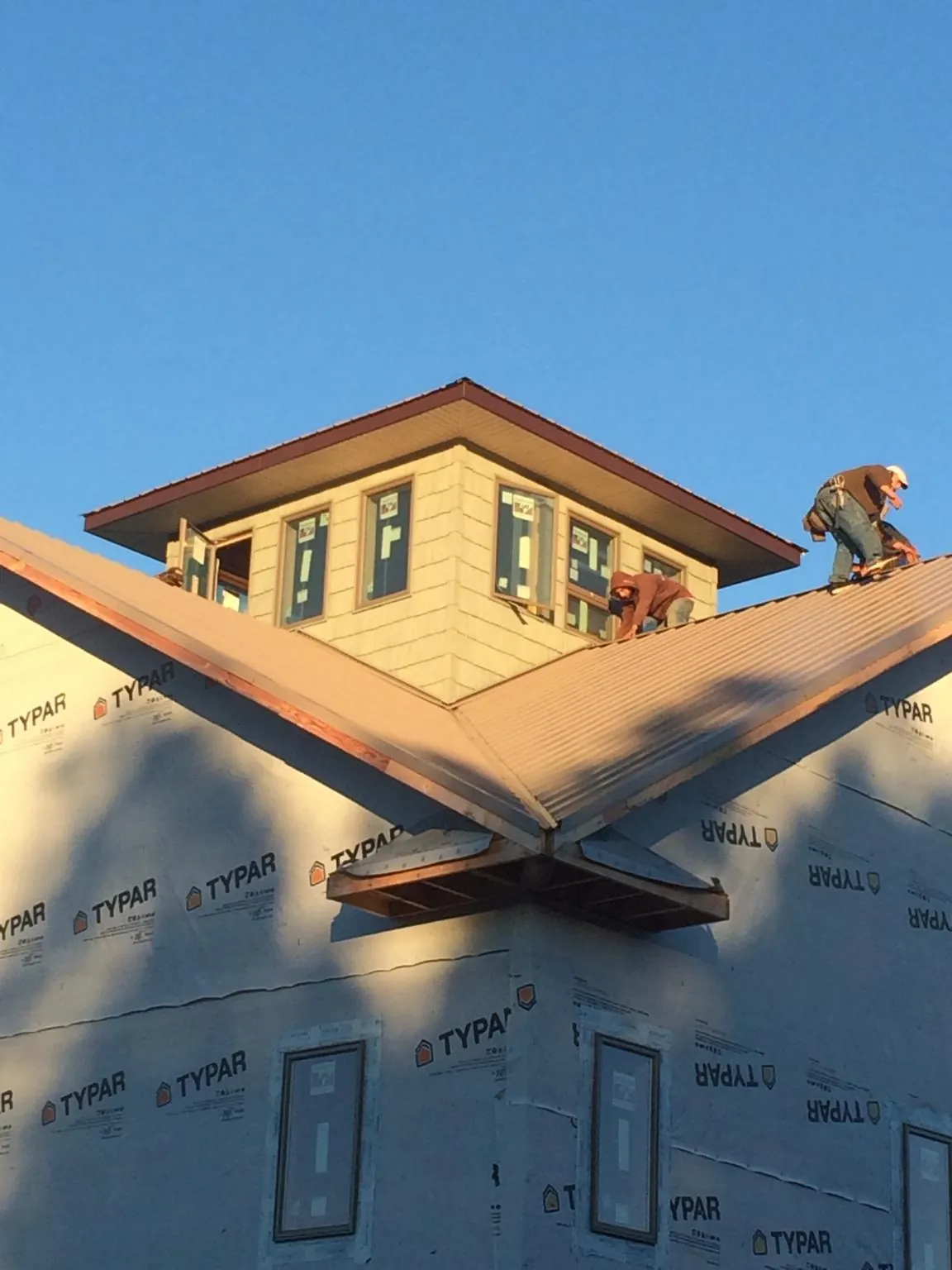 Roofers working around a rooftop cupola on a new metal roof at sunset — Roof Waterproofing in North East by Roofing Brothers
